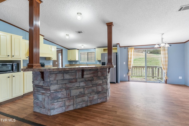 kitchen with cream cabinets, stainless steel appliances, visible vents, vaulted ceiling, and ornamental molding