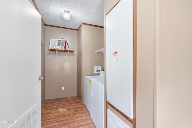 laundry room featuring laundry area, washer and clothes dryer, ornamental molding, a textured ceiling, and light wood-type flooring