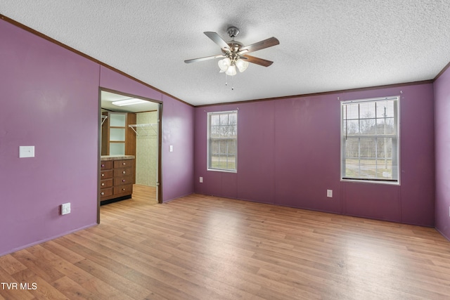 unfurnished bedroom with ornamental molding, multiple windows, a textured ceiling, and wood finished floors