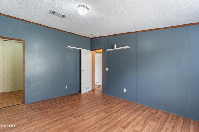 unfurnished room with ornamental molding, visible vents, a textured ceiling, and light wood finished floors