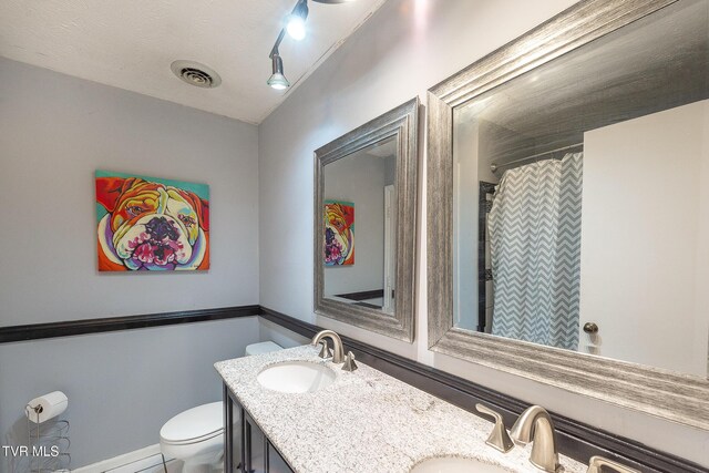 bathroom featuring visible vents, a sink, toilet, and double vanity