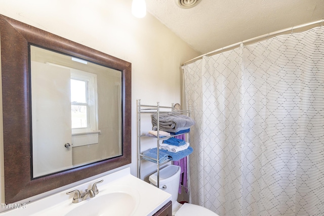 bathroom featuring a textured ceiling, curtained shower, vanity, and toilet