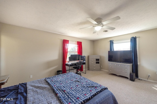 carpeted bedroom with ceiling fan, multiple windows, a textured ceiling, and baseboards