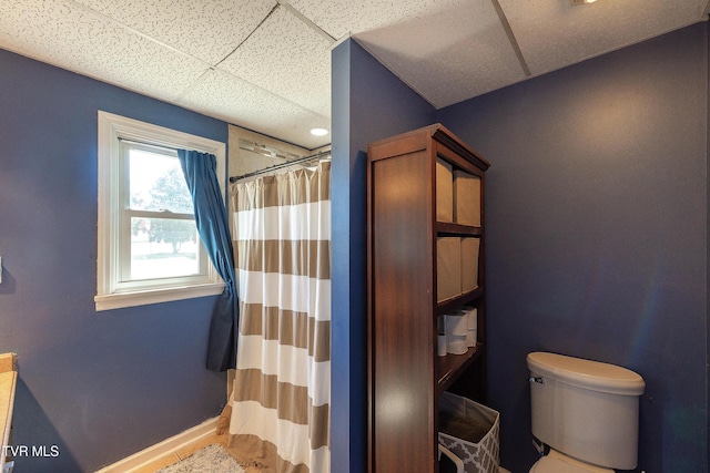 full bathroom featuring a paneled ceiling, baseboards, a shower with shower curtain, and toilet