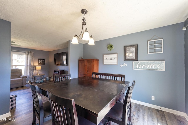 dining space with visible vents, a textured ceiling, baseboards, and wood finished floors