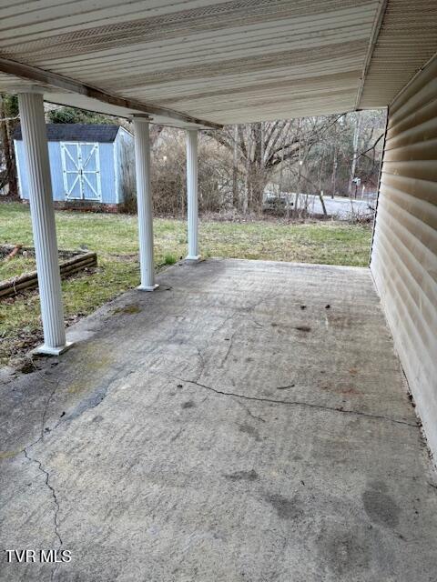 view of patio with a carport, an outbuilding, and a storage shed