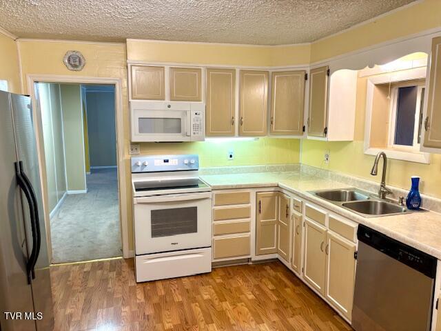 kitchen with stainless steel appliances, light countertops, a sink, and wood finished floors