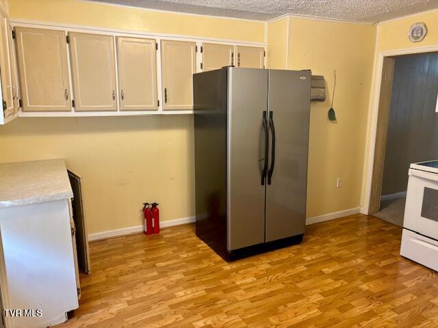 kitchen with white range with electric cooktop, light countertops, freestanding refrigerator, a textured ceiling, and light wood-type flooring