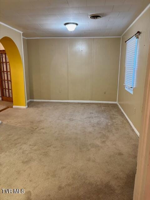 spare room with baseboards, arched walkways, carpet flooring, and ornamental molding