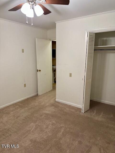 unfurnished bedroom featuring carpet floors, baseboards, ornamental molding, and a closet