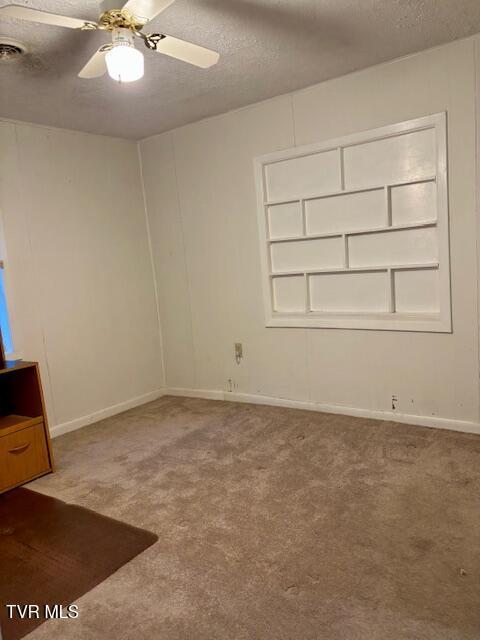 carpeted empty room with a ceiling fan, a textured ceiling, and baseboards