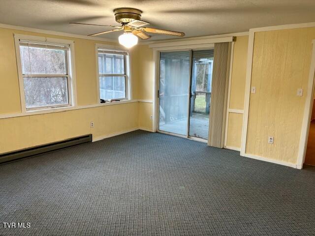 empty room featuring ceiling fan, a baseboard radiator, baseboards, dark carpet, and crown molding