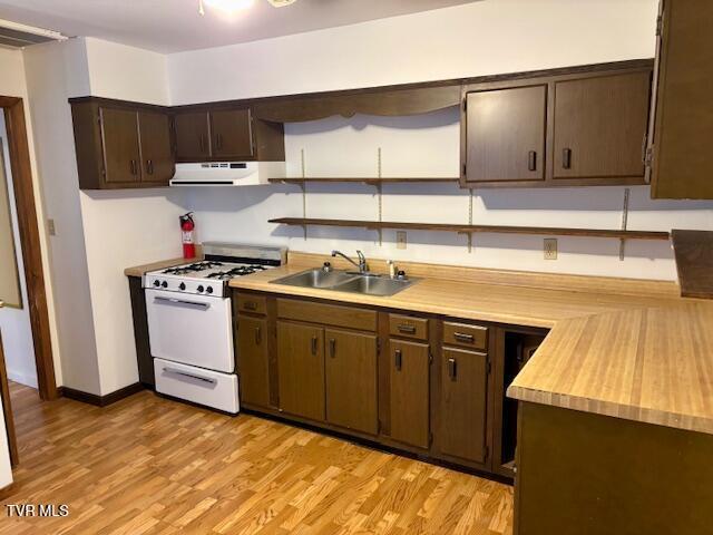 kitchen featuring white gas range, light countertops, light wood-style flooring, a sink, and extractor fan