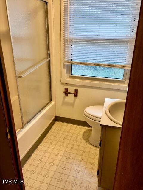 full bathroom with toilet, bath / shower combo with glass door, vanity, baseboards, and tile patterned floors