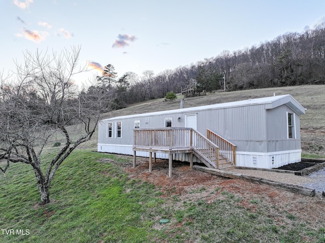 view of front facade with a wooden deck and a front lawn