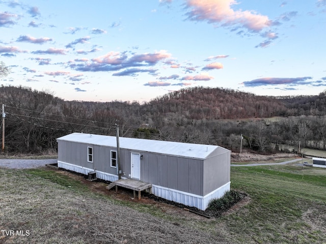 view of front of house featuring a front yard, central AC unit, and a wooded view