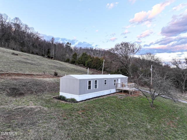 exterior space featuring a view of trees, a deck, and a front yard