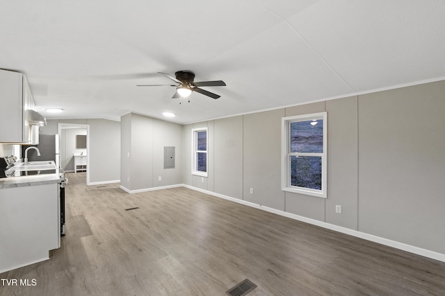 unfurnished living room featuring visible vents, a ceiling fan, electric panel, a sink, and wood finished floors