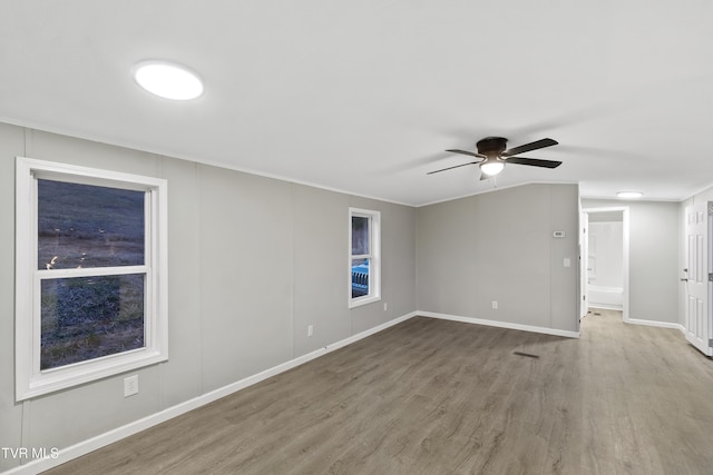 empty room with vaulted ceiling, wood finished floors, baseboards, and ceiling fan