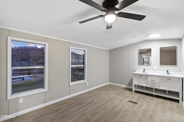 interior space with a sink, visible vents, light wood-style floors, and vaulted ceiling