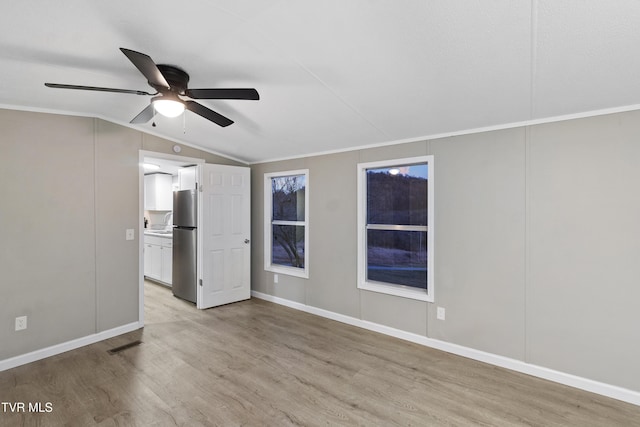 interior space with visible vents, a ceiling fan, baseboards, light wood finished floors, and lofted ceiling