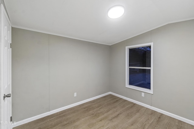 empty room featuring baseboards, lofted ceiling, and wood finished floors