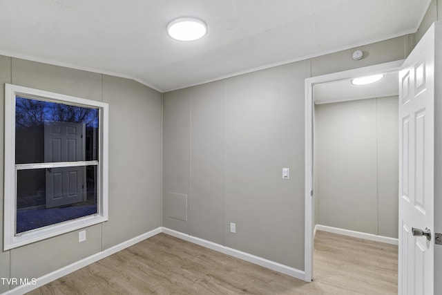 empty room featuring baseboards, lofted ceiling, and wood finished floors