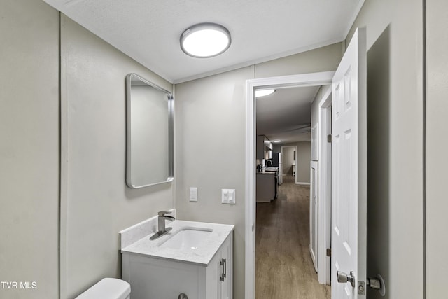 half bathroom with toilet, vanity, and wood finished floors