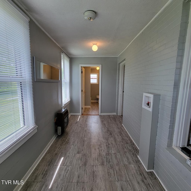 204 Highland Ave, Glade Spring, VA 24340 - hall with a textured ceiling, wood finished floors, brick wall, and ornamental molding