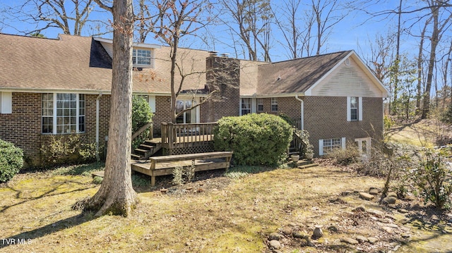 rear view of property featuring brick siding, a deck, and a chimney