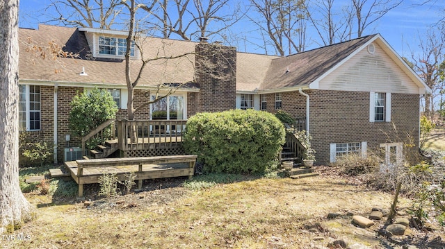 rear view of property with brick siding, a wooden deck, stairs, roof with shingles, and a chimney