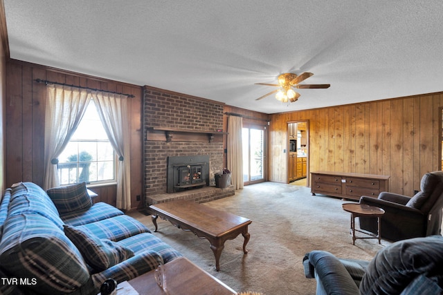 living room with a wealth of natural light, light colored carpet, wood walls, and a textured ceiling