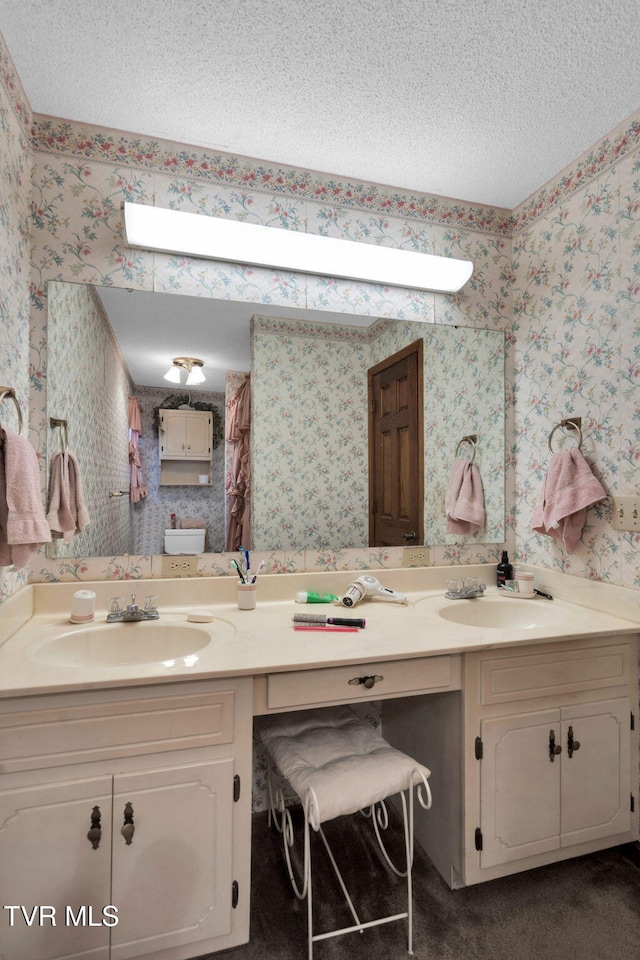 full bathroom featuring a textured ceiling, wallpapered walls, and vanity