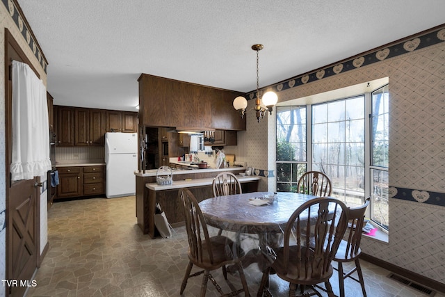 dining area with stone finish flooring, a textured ceiling, and wallpapered walls