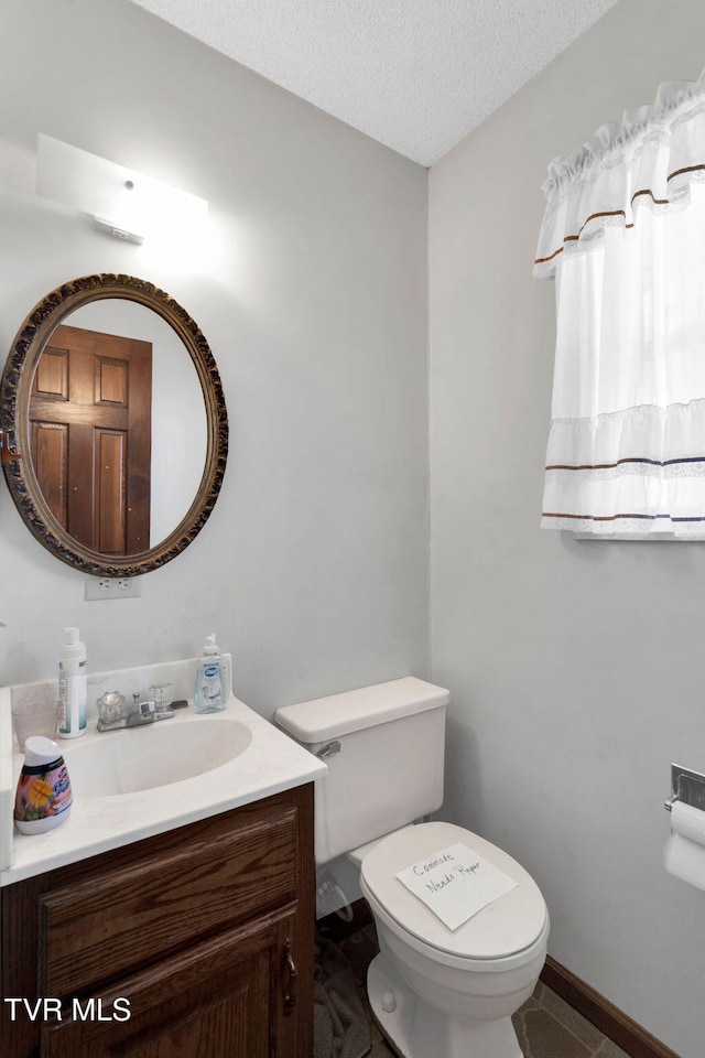 bathroom featuring a textured ceiling, vanity, and toilet