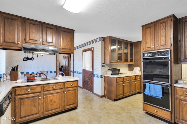 kitchen with dishwashing machine, wallpapered walls, light countertops, glass insert cabinets, and dobule oven black