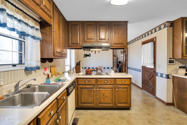 kitchen with wallpapered walls, under cabinet range hood, light countertops, white appliances, and a sink