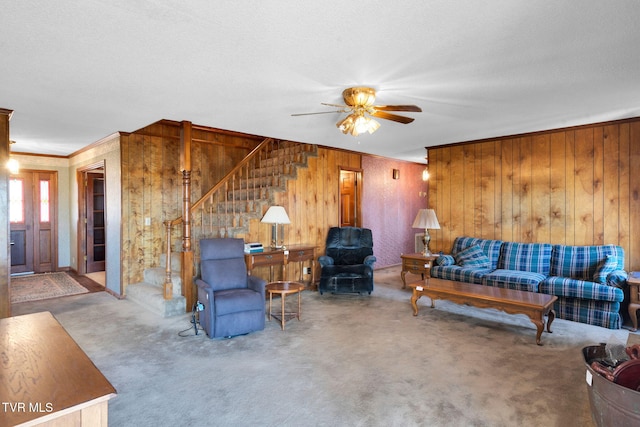 carpeted living room featuring a ceiling fan, ornamental molding, stairs, and a textured ceiling