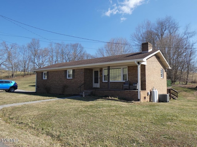 ranch-style home with a front yard, brick siding, a chimney, and central air condition unit