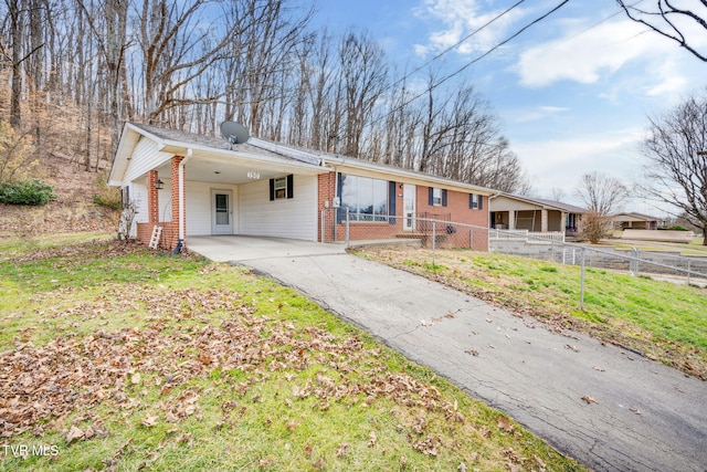 ranch-style home with a carport, a fenced front yard, brick siding, and driveway