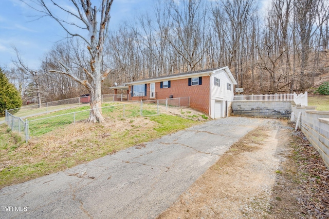 view of front of house featuring aphalt driveway, an attached garage, fence, and brick siding