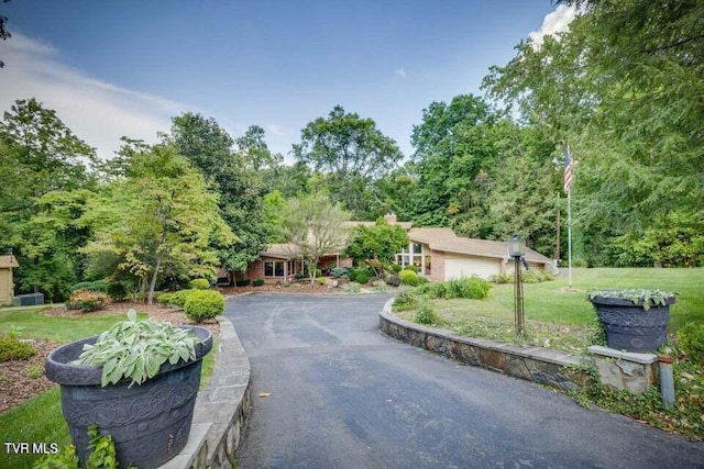 single story home featuring aphalt driveway, a garage, and a front lawn