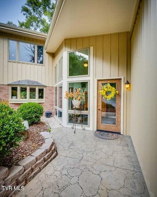 doorway to property with board and batten siding and brick siding