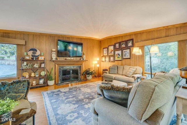 living room with ornamental molding, wood finished floors, wood walls, and a premium fireplace