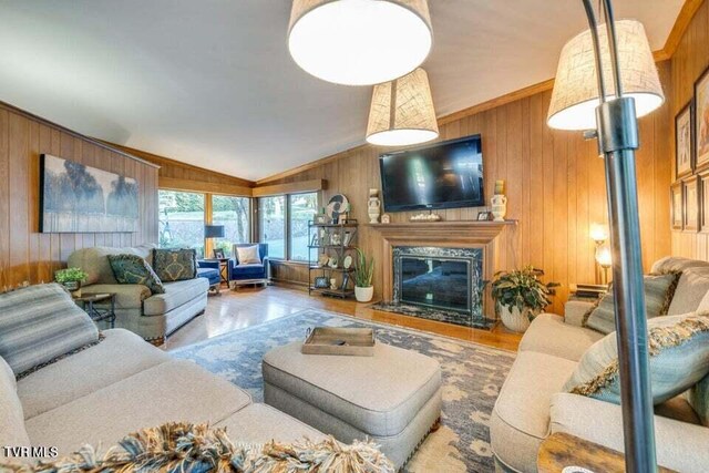 living room with a premium fireplace, wooden walls, wood finished floors, and vaulted ceiling