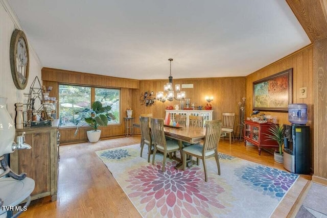 dining space with an inviting chandelier, wooden walls, and wood finished floors