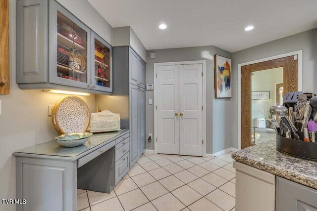 kitchen featuring gray cabinetry, glass insert cabinets, baseboards, light tile patterned floors, and recessed lighting