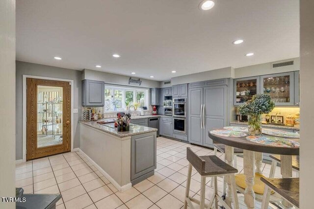 kitchen featuring visible vents, gray cabinetry, light tile patterned floors, a peninsula, and paneled built in refrigerator