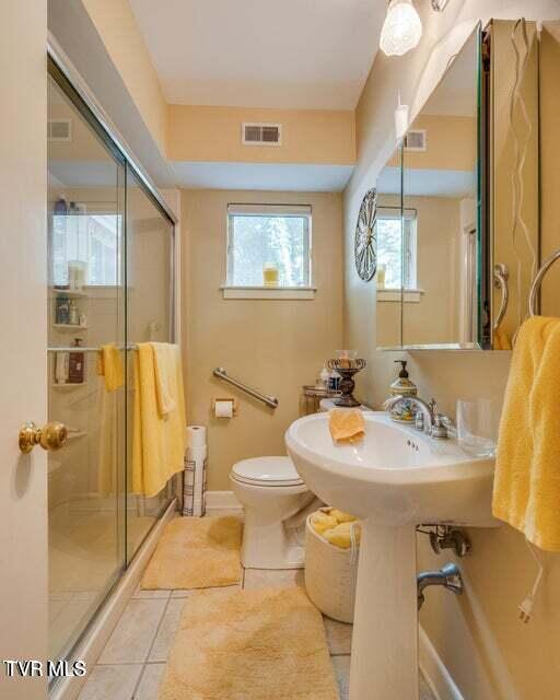 bathroom with tile patterned floors, visible vents, a stall shower, and toilet