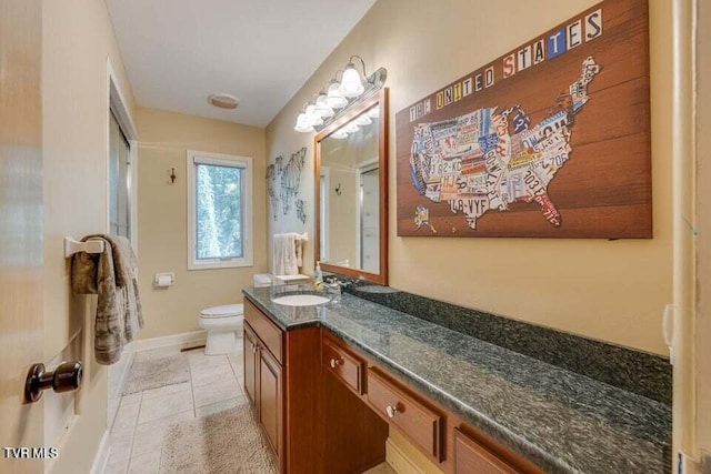 bathroom with baseboards, toilet, vanity, and tile patterned flooring